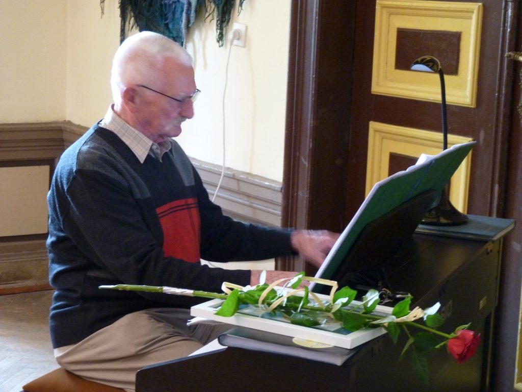 Pianista Grzegorz Ciejpa przy pianinie na finisażu wystwy